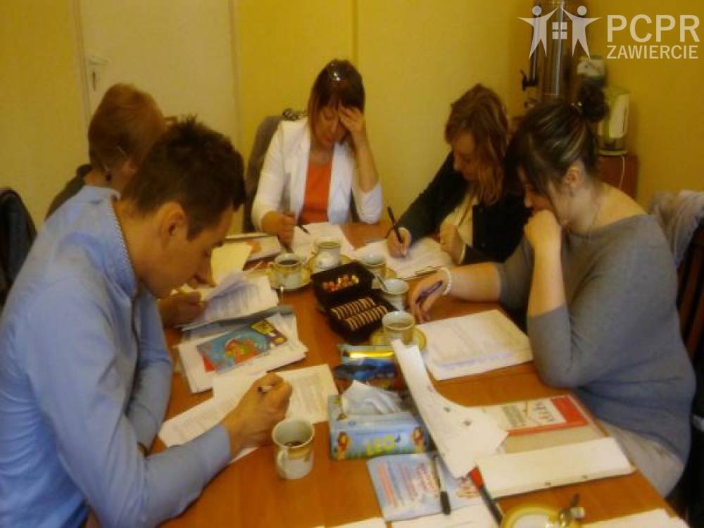 Zdjęcie: 4 kobiety i mężczyzna siedzą przy stole czytając dokumenty
